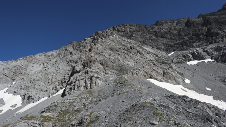 Eine Pfadspur im Geröll führt an den Fuss der Felsen.