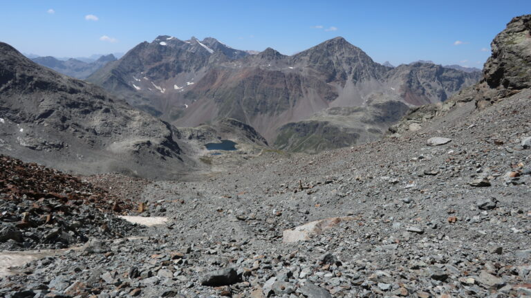 Pfosten und Steinmänner im Geröllkessel zeigen den Weg.