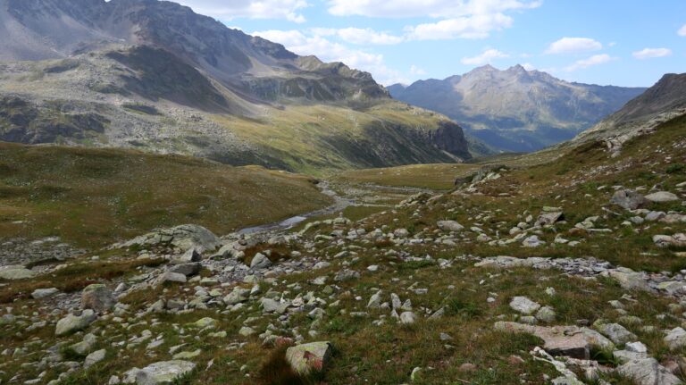Steinmanndeln leiten auf eine Ebene mit Bach.